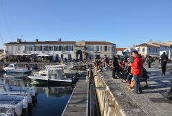 Hafen mit kleinen Booten im Vordergrund, im Hintergrund Gebäude