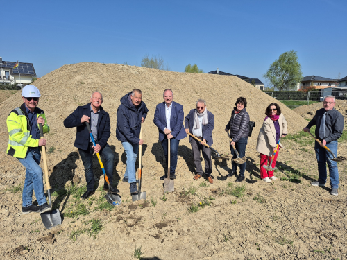 Der Bürgermeister, die Fraktionsvorsitzende aus dem Gemeinderat und Projektbeteiligte führen symbolisch den Spatenstich auf der Baustelle aus.
