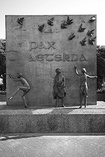 Wand mit dem Schriftzug "pax eterna" in die fliegende Tauben eingearbeitet sind. Davor stehen die Skulpturen von drei Kindern.